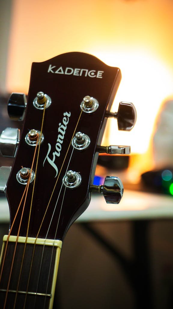 Detailed close-up of an acoustic guitar headstock indoors with a warm tone.