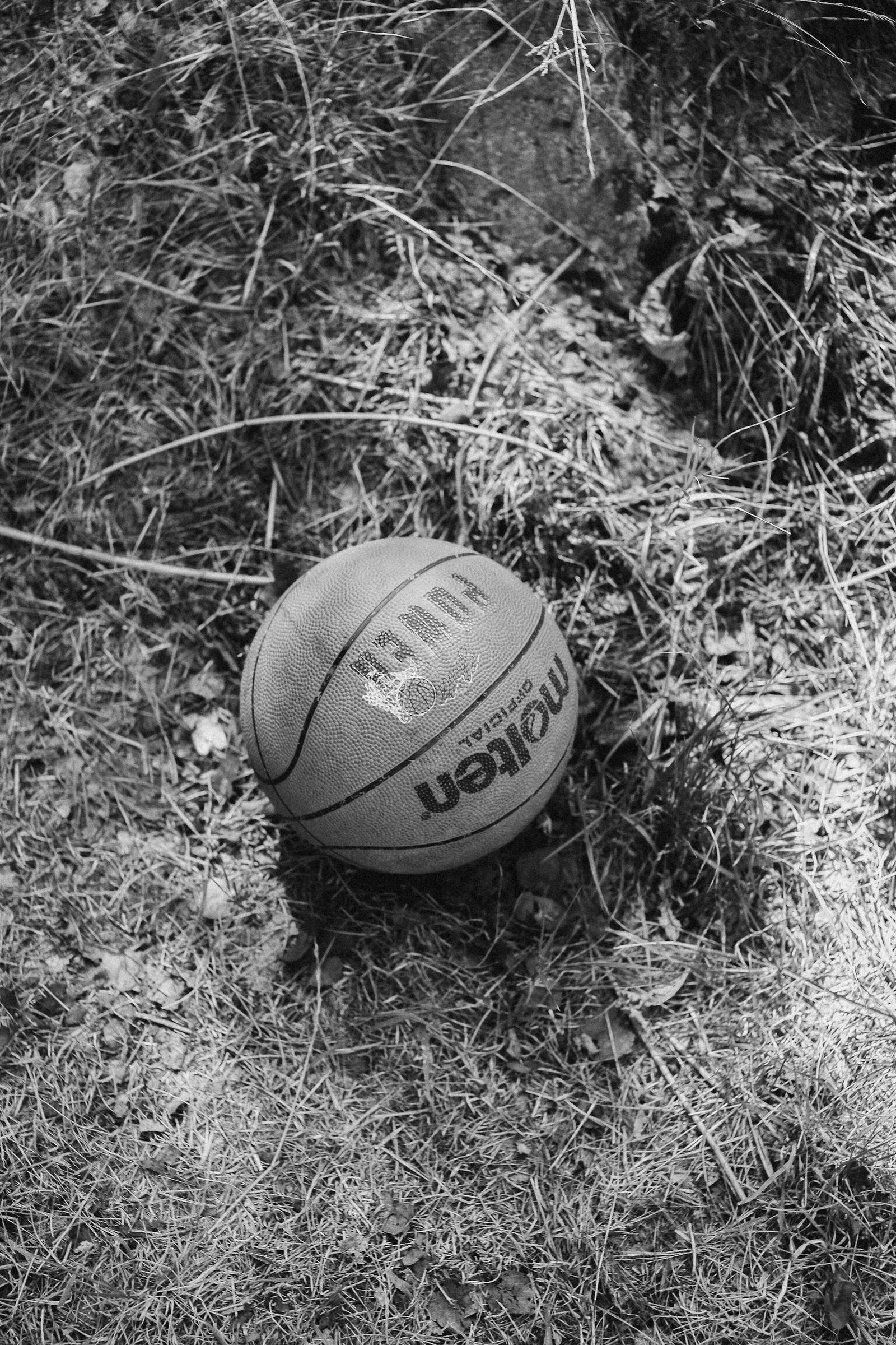 Grayscale basketball lying on textured grass outdoors.