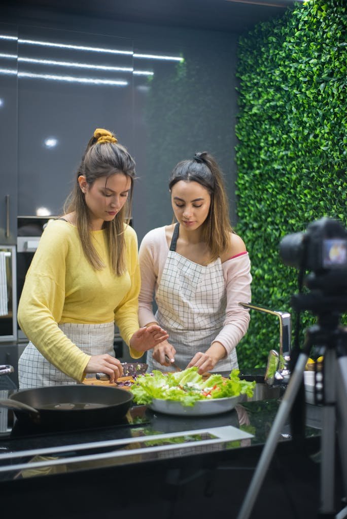 Two women preparing a meal in a stylish kitchen with green accents.